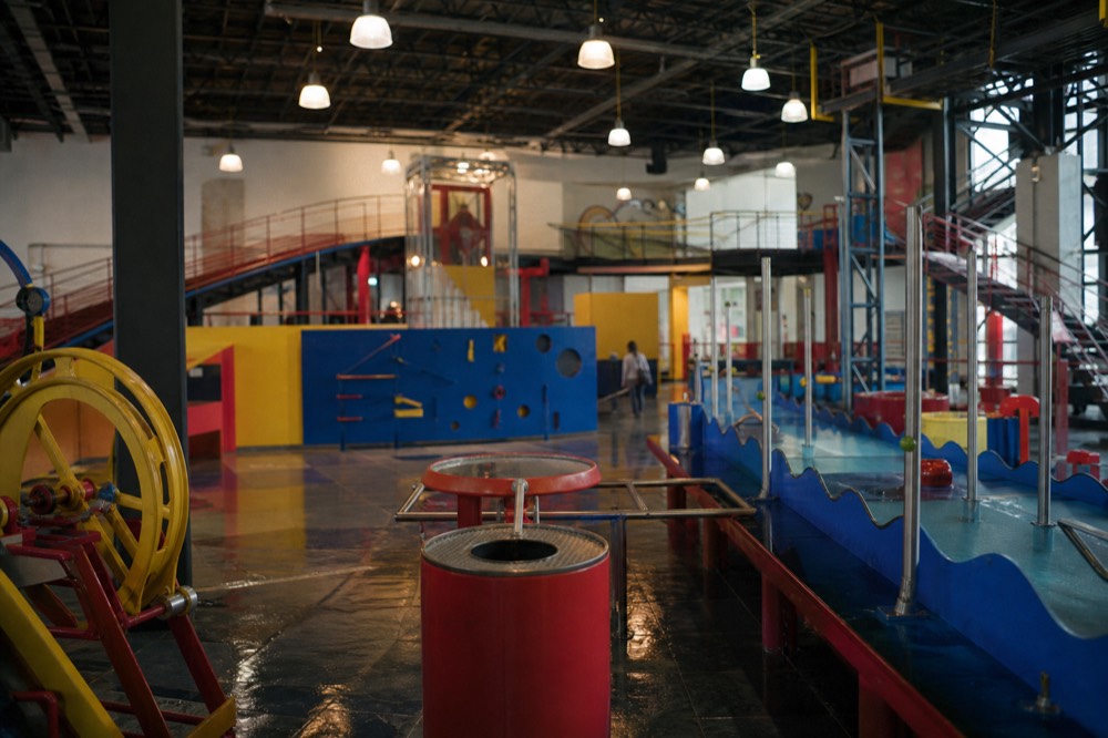 Children climbing on a large interactive play structure inside a bright children's museum gallery